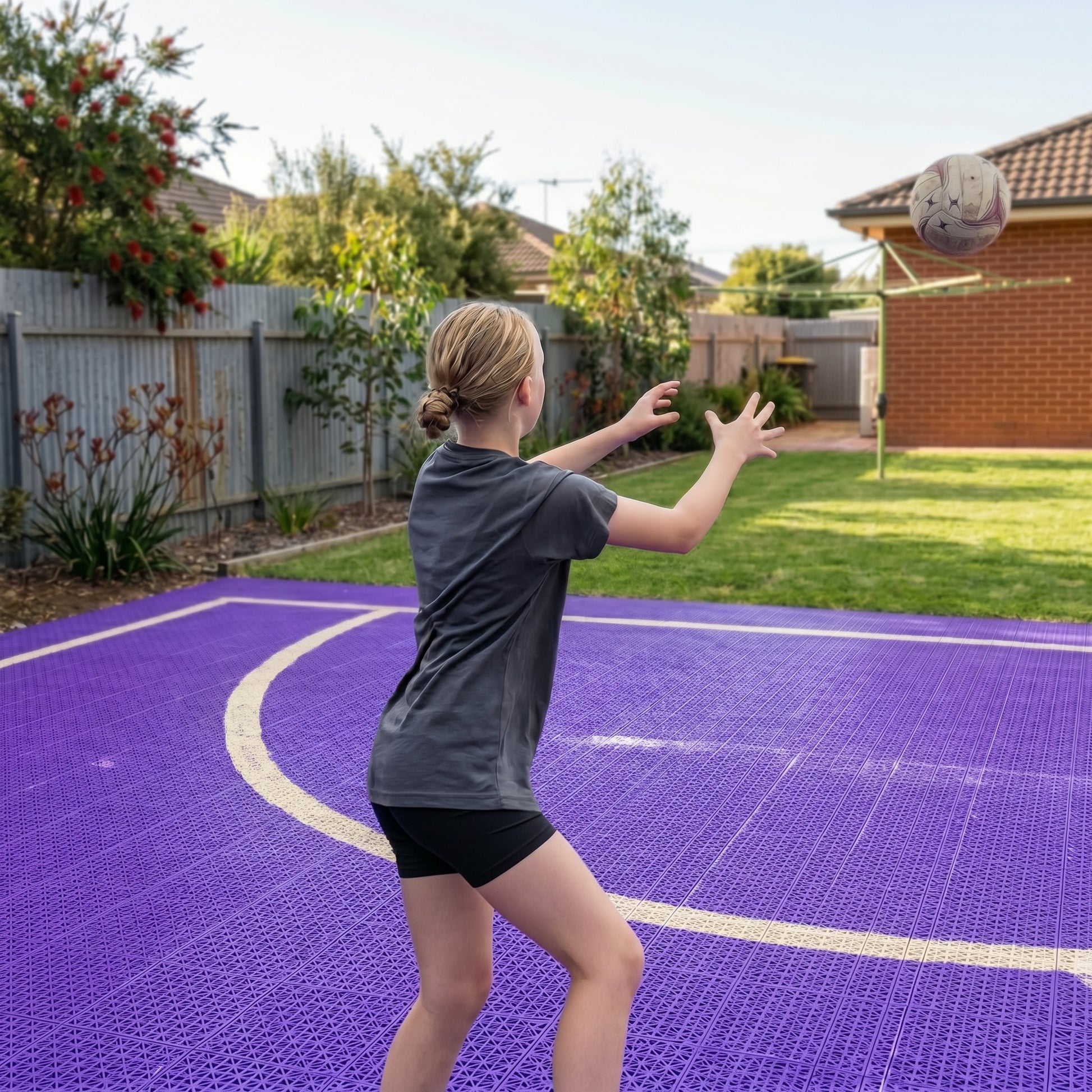 Person playing basketball on a purple court with a residential background